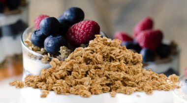 pile of granola over three fruit parfait in glass