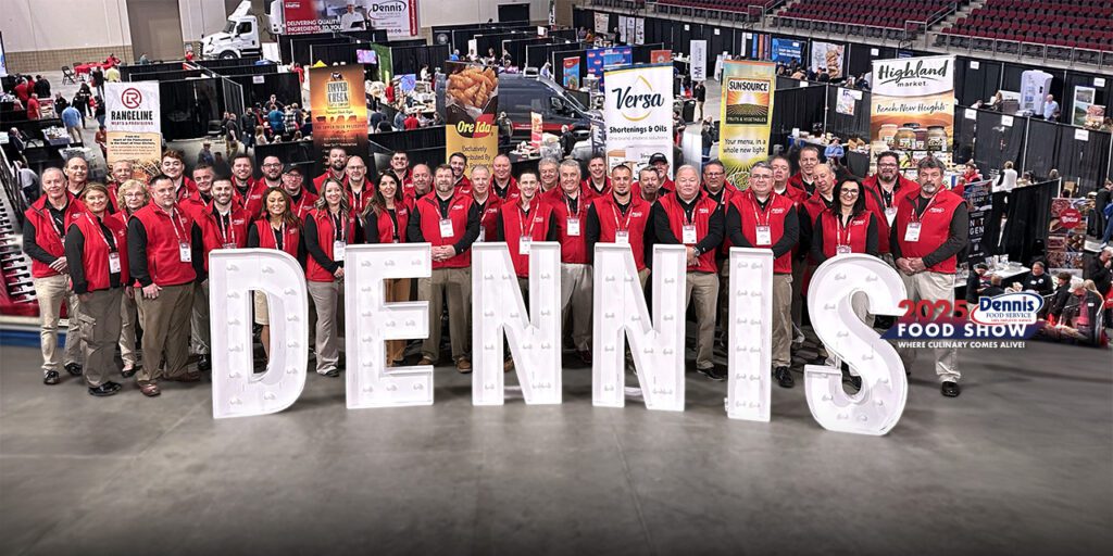 team in red vests behind tall white letters that say DENNIS