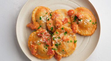 plate with 5 prepared mini raviolis with sauce and spices covered.