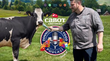 podcast logo in front of man holding microphone out to a cow in a farm field