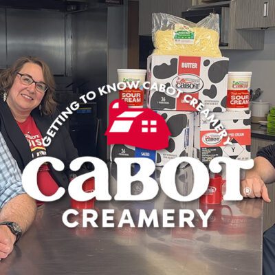 cabot logo in front of 3 people at a metal table in a kitchen looking at the camera