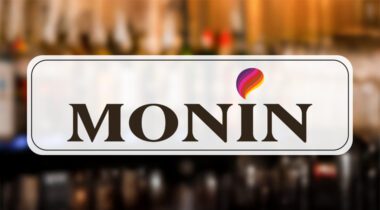 Large Monin logo over out of focus image