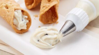 vanilla canoli filling on plate with three canolis on same plate