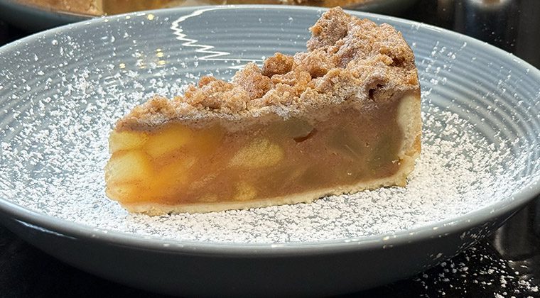 a slice of apple crumb cake on a plate with powdered sugar