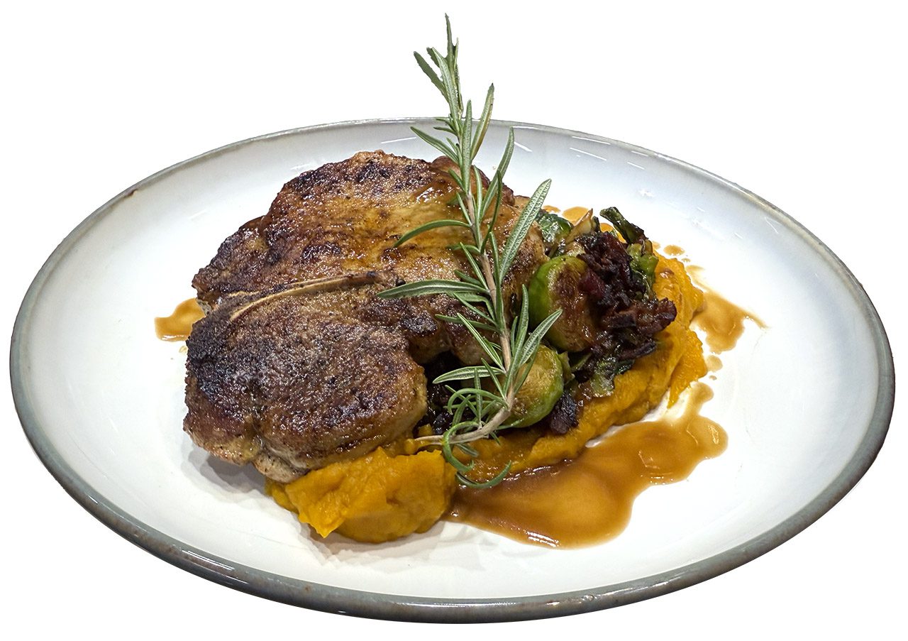 pork porterhouse steak on plate with sweet potato mash and rosemary sprif
