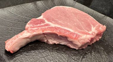 a Frenched bone-in pork chop on a black plate