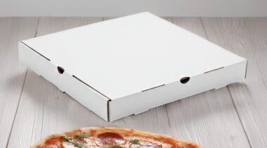 Square, white pizza box on wood tabletop next to pizza