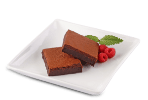 white plate with two squares of fudge brownies and three raspberries and mint leaf.