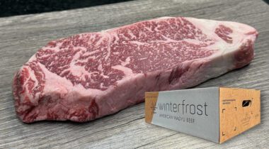 raw wagyu strip loin steak on gray plank with beef box inset