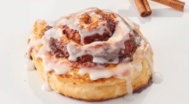 baked cinnamon roll with white drizzles of frosting
