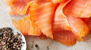 thin slices of pink salmon on table with pepper spices