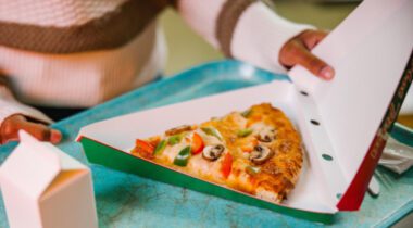 slice of veggie pizza in opened triangle paper box