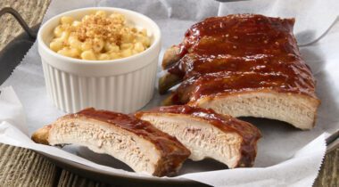 plate of prepared bbq pork ribs with bowl of macaroni and cheese