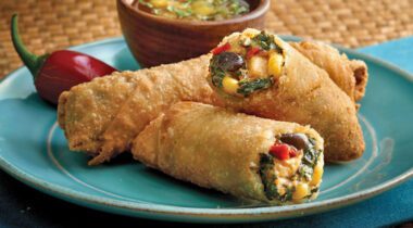 three vegetable, bean, and chicken egg rolls on blue plate