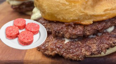 double cheese burger with crisp thin burger patties sticking out from bun, white cheese, and 4 raw burger pucks inset on the left