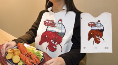 white disposable lobster bib, person wearing lobster bib seated at a lobster dinner