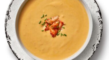 top view of red-orange creamy soup (lobster bisque) in a bowl