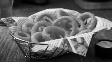 gray image of onion rings in a basket