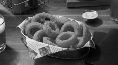 gray image of onion rings in a basket