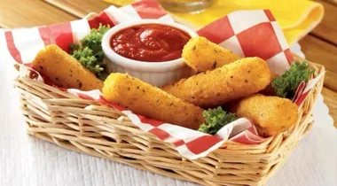 breaded mozzarella sticks in a wicker basket with checkered parchment paper and a ramekin of marinara